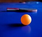 Vibrant orange ping pong ball with a table tennis racket on a blue table, emphasizing sport and leisure.